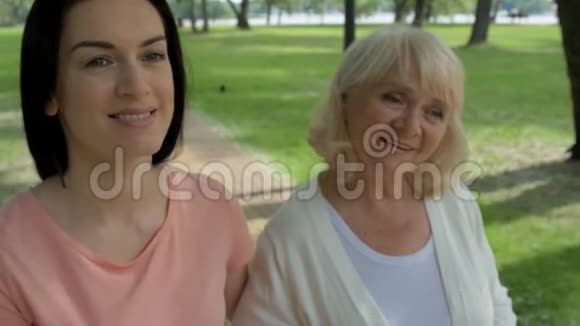 可爱的女人和她的高级母亲在公园里散步视频的预览图
