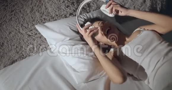 床上戴耳机的快乐女人视频的预览图