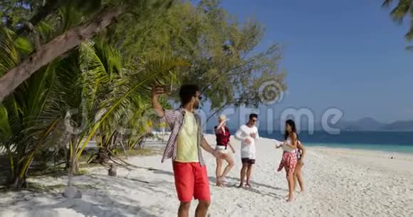 西班牙裔打电话的人在沙滩上的男女游客交流手机上自拍视频的预览图