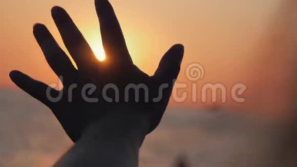 日落时分女性在太阳下手特写海上夕阳暖女手视频的预览图