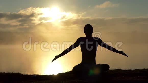 闪亮的瑜伽士坐在湖岸的莲花中缓慢地祈祷日落视频的预览图