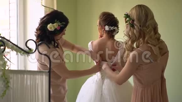 两个女朋友帮新娘穿衣每个人都在微笑女孩们都用花装饰视频的预览图