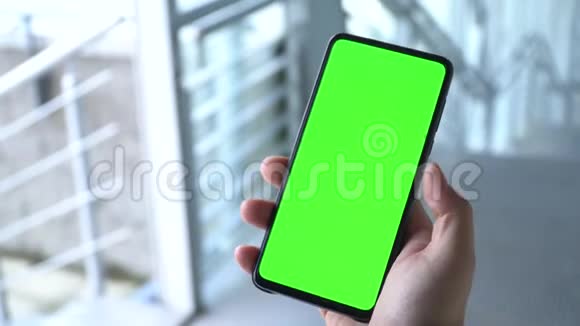 绿色屏幕智能手机一个男人手拿着电话在手机的绿色屏幕上滚动智能手机录像视频的预览图