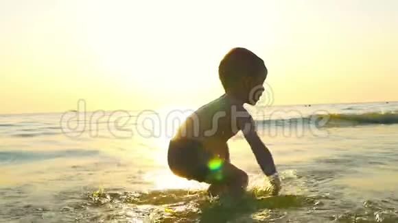 小男孩在大海上玩水在扑面而来的海浪中在夕阳的映衬下视频的预览图