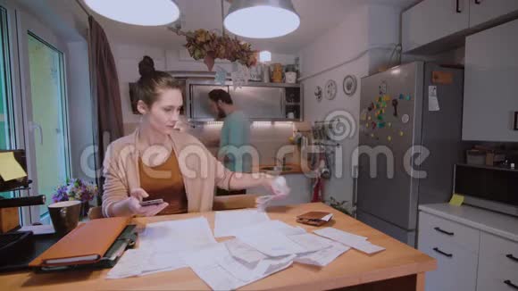 年轻夫妇一起在厨房里计算家庭预算在有压力的情况下设法保证钱的安全视频的预览图