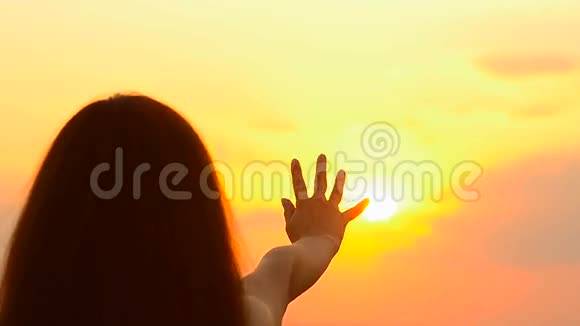女孩拉着一只手对着金色的太阳视频的预览图