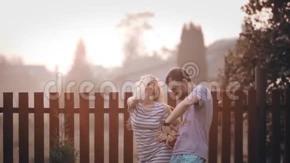 年轻快乐的夫妇在后院一起玩在日落开朗的男人和女人在外面跳舞视频的预览图