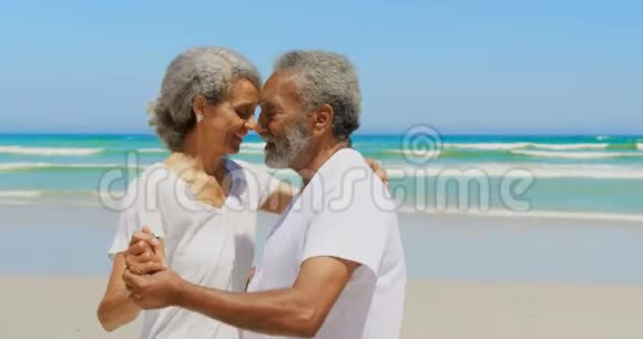 浪漫活跃的老年非裔美国夫妇在海滩上跳舞的侧面景色视频的预览图