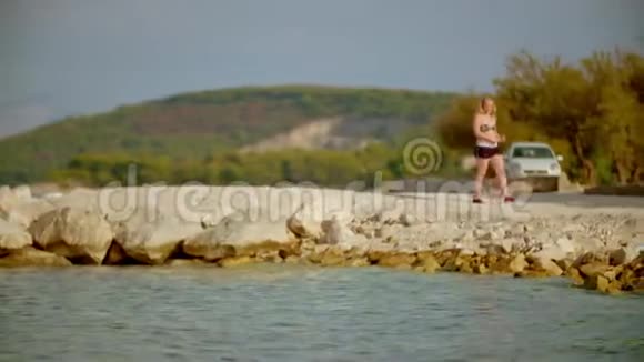 坐在海滨岩石上的女人视频的预览图