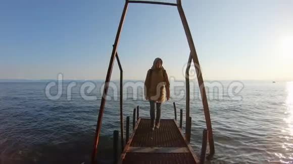 一个女孩沿着海滩上的码头散步视频的预览图