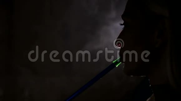 一个女孩在黑色背景上抽烟的剪影视频的预览图