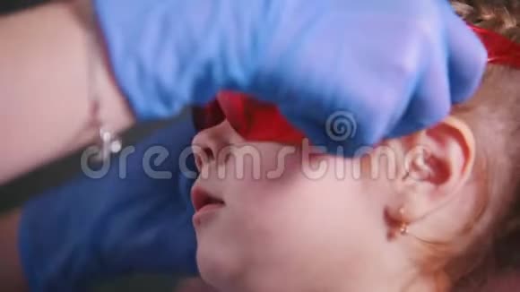 牙医医学牙医将防护眼镜戴在婴儿脸上并使用牙科治疗灯视频的预览图
