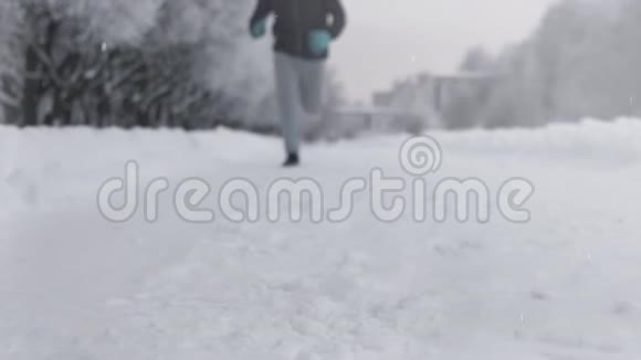 冬天在公园里沿着雪道奔跑的人的剪影视频的预览图