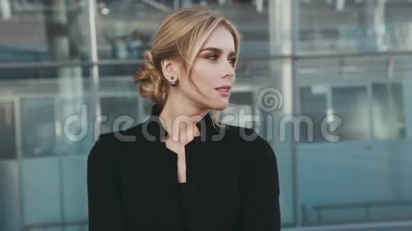 美丽的金发女郎穿着时尚的黑色服装时尚的配饰和机场外的天然妆容视频的预览图