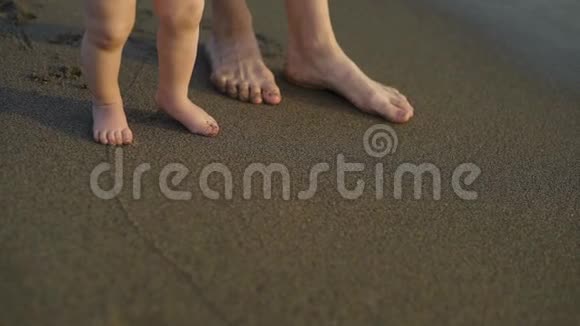 一个小婴儿赤脚走在沙滩上妈妈教孩子走路视频的预览图