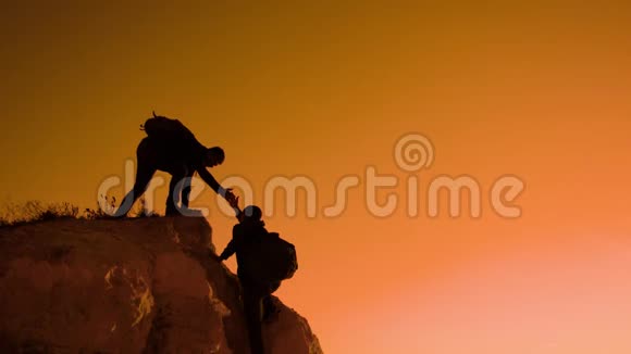 两个男子协同游客爬上一座山徒步旅行者徒步旅行冒险登山日落攀登视频的预览图