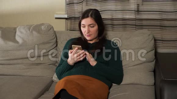 年轻女子坐在沙发上拿着电话视频的预览图