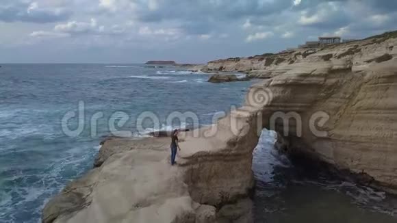 一个女孩爬上海边的岩石视频的预览图