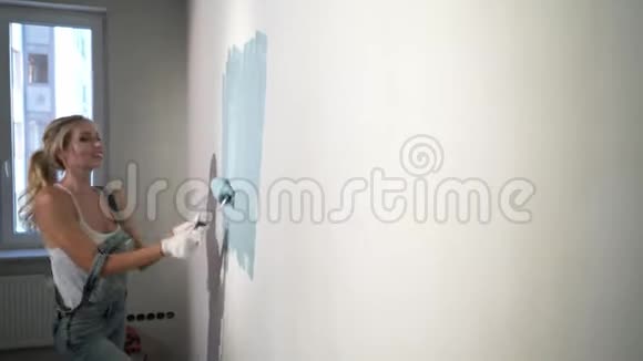 施工现场的年轻女建筑工用油漆滚筒视频的预览图