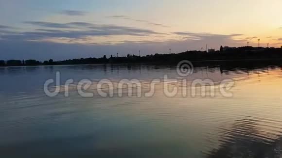 美丽的日落在城市的地平线上在一个寂静的夏天的傍晚倒影在平静的湖水上视频的预览图