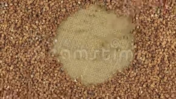 落的荞麦颗粒在旋转的荞麦圆圈上躺在麻布上视频的预览图