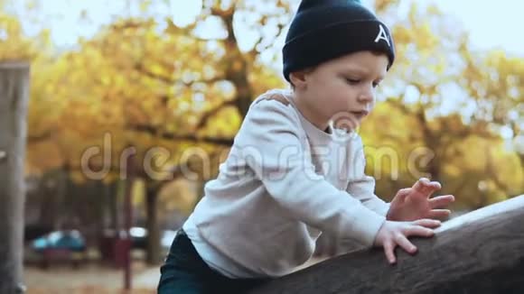 学龄前白人男孩在操场上玩得很开心困惑紧张的孩子戴着帽子卡在高绳道障碍上视频的预览图