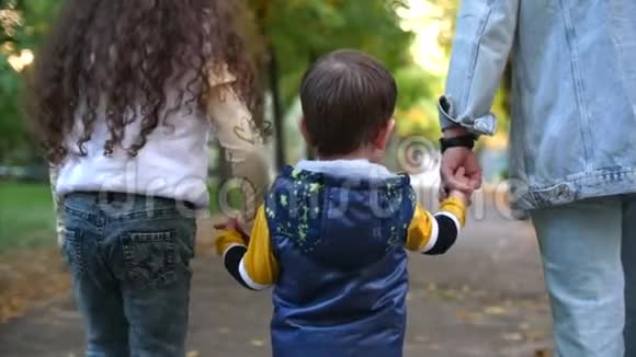 幸福的家庭妈妈和孩子们牵手散步家庭的概念母亲和年轻人一起在公园散步视频的预览图