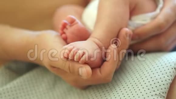 一个刚出生婴儿的腿在他父亲手掌上特写男性的温柔接触皮肤到皮肤父亲节视频的预览图