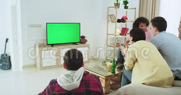 兴奋的一群多民族朋友在电视上用绿色屏幕观看足球比赛他们高兴地支持和支持视频的预览图