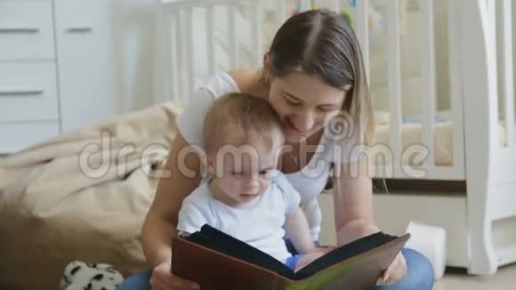 快乐的年轻妈妈和她的小儿子在客厅地板上看家庭相册视频的预览图