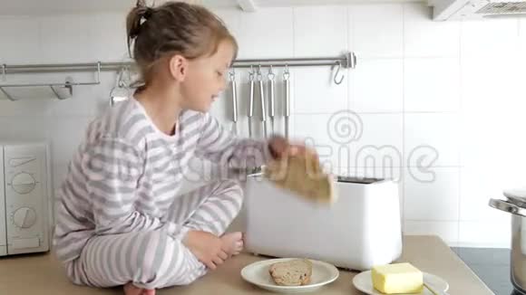 穿着睡衣把面包放进烤面包机的女孩视频的预览图