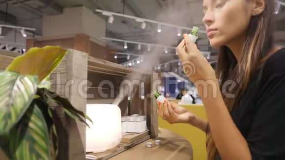 年轻的高加索女人在购物中心为扩散器选择芳香油4K视频的预览图
