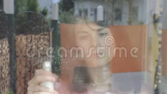 年轻女子打扫窗户透过窗户看起来很生气视频的预览图