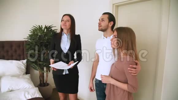 女房地产经纪人会见年轻夫妇展示公寓卧室视频的预览图