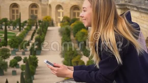 年轻女性使用智能手机与凡尔赛背景慢动作视频的预览图