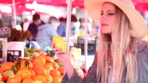 市场上的金发女孩闻着水果视频的预览图