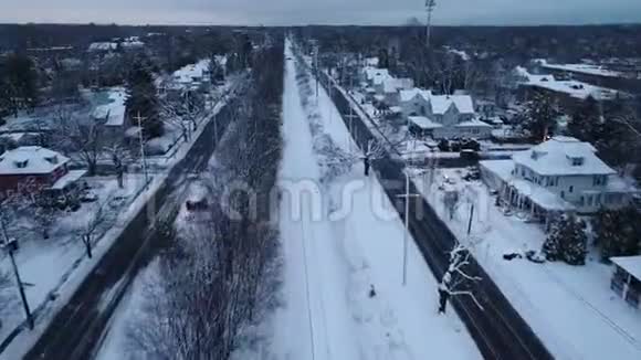 冬天寒冷的一天一个被雪覆盖的小镇上的铁轨的鸟瞰图视频的预览图