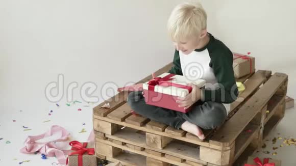 金发男孩打开一个带礼物的盒子视频的预览图