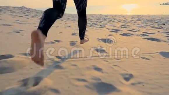 健康年轻的运动美女沿着沙滩奔跑在沙滩上在夏天向太阳奔跑在日出时视频的预览图
