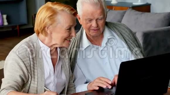 老年夫妇用笔记本电脑上网快乐的老人使用电脑视频的预览图