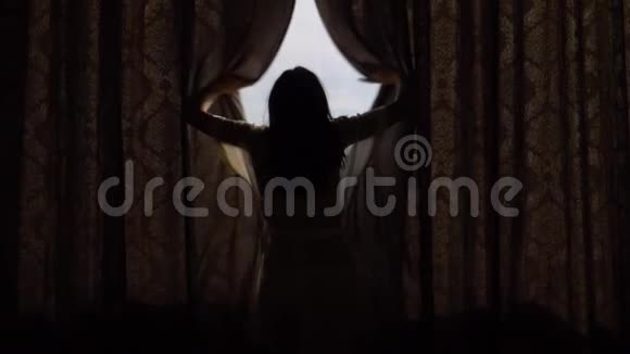 一个阳光明媚的早晨幸福的女人在屋中窗外拉开帷幕视频的预览图