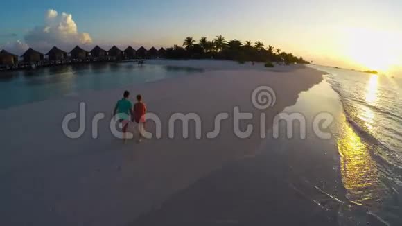 在热带海滩日落时两个相爱的人空中视频的预览图