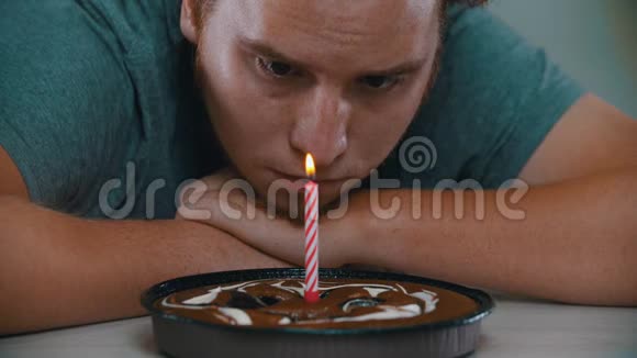 一个男人正在看蛋糕上的蜡烛视频的预览图