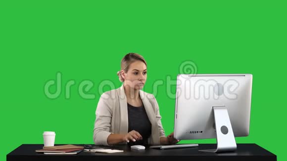 漂亮的金发女人在绿色屏幕上的电脑上工作Chroma键视频的预览图