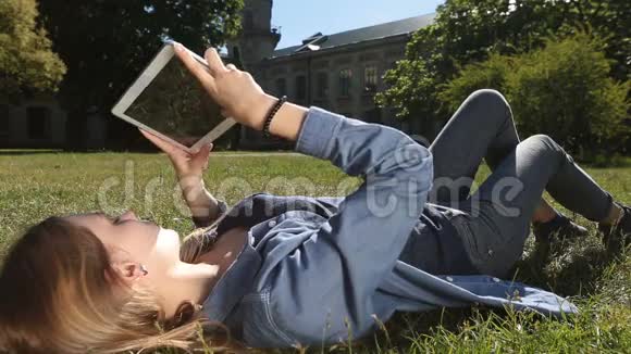 可爱的女学生在公园用平板电脑学习视频的预览图