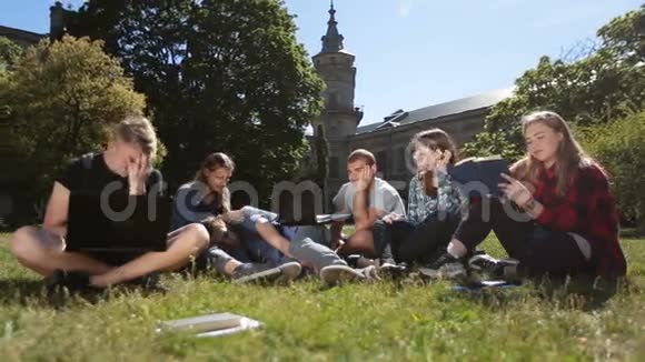 疲惫的年轻学生在校园草坪上学习视频的预览图