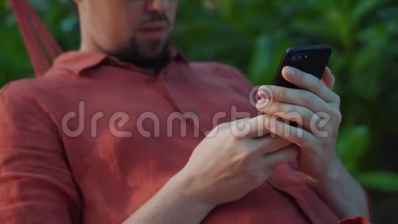 男人在花园的智能手机上打字视频的预览图