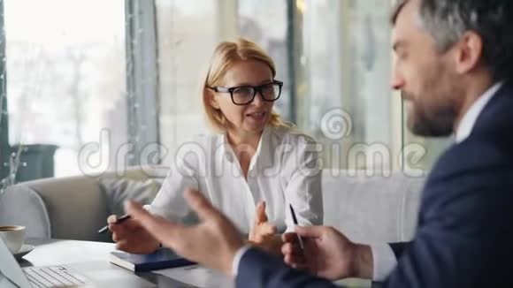 商业伙伴开朗的男人和女人在咖啡馆里聊天看报纸视频的预览图