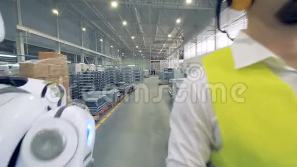 工厂工人和一个机器人一起在工厂里行走视频的预览图
