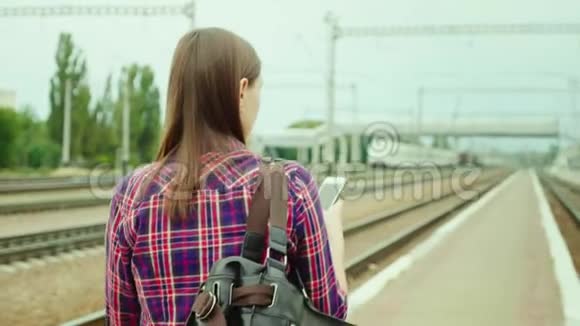后面一个漂亮的年轻女人沿着铁路站台走使用手机理念是成功的视频的预览图